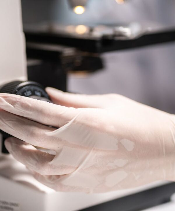 Scientist working with a microscope in a medical research lab, emphasizing advanced quality control for bacteriophage solutions at Qeen Biotechnologies.