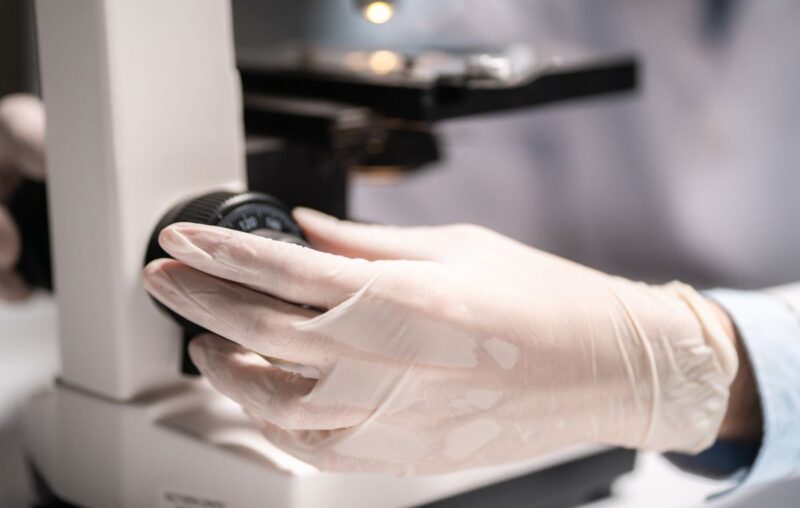 Scientist working with a microscope in a medical research lab, emphasizing advanced quality control for bacteriophage solutions at Qeen Biotechnologies.