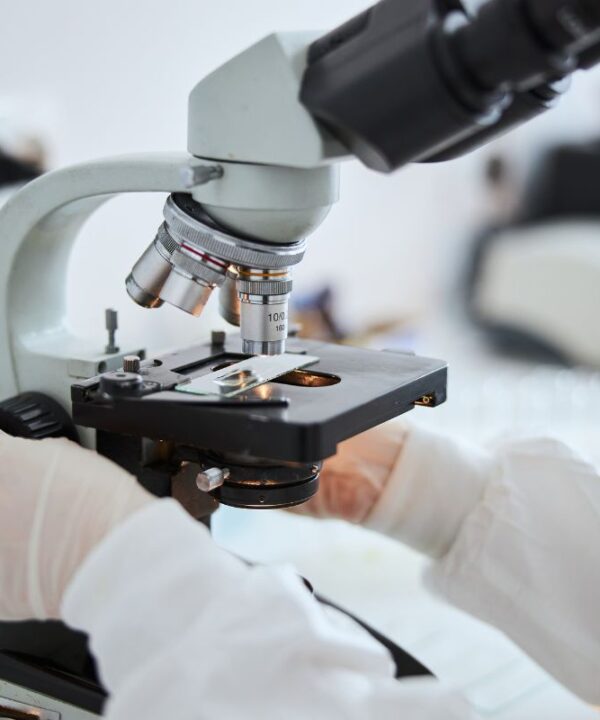 Scientist's hand working with a microscope, illustrating expert cell banking solutions for reliable bacteriophage production.