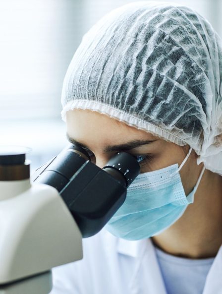 Scientist analyzing bacteria under a microscope, highlighting advanced scientific research.