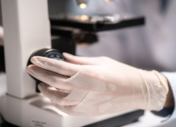 Scientist working with a microscope in a medical research lab, emphasizing advanced quality control for bacteriophage solutions at Qeen Biotechnologies.