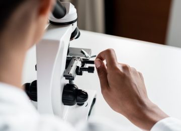 Scientist working with a microscope, highlighting advanced downstream processing techniques for high-quality bacteriophage production at Qeen Biotechnologies.